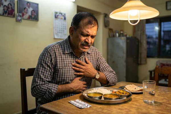 Indian man experiencing acid reflux discomfort after a meal